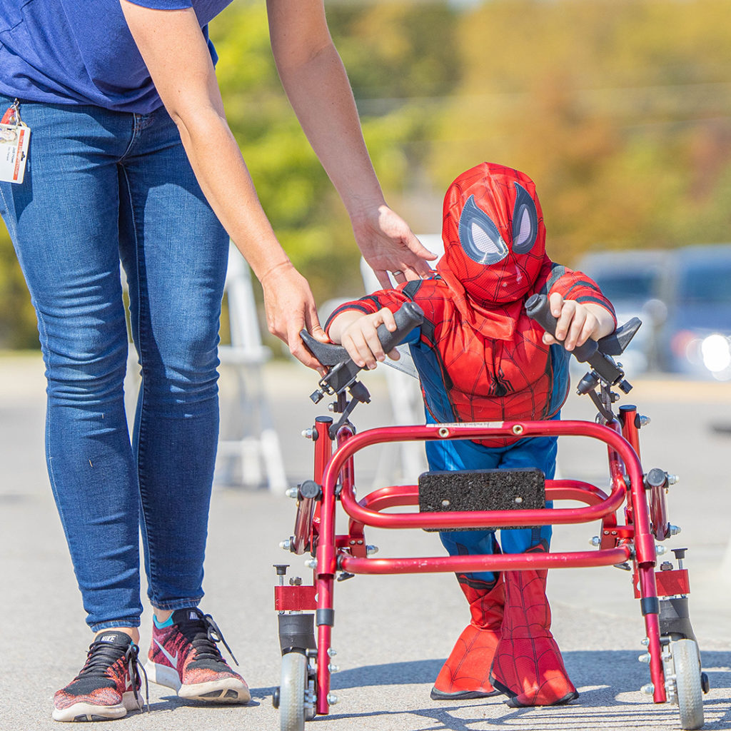 Kid in spider man suit pushing a walker