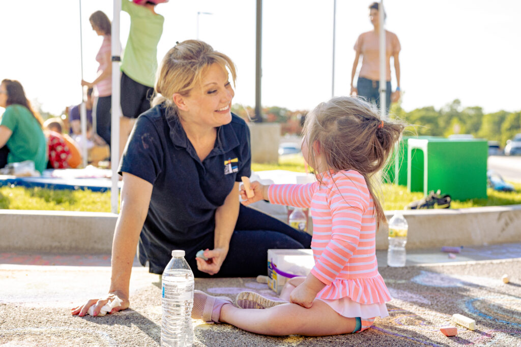 teacher smiling lovingly at a little girl with down syndrome