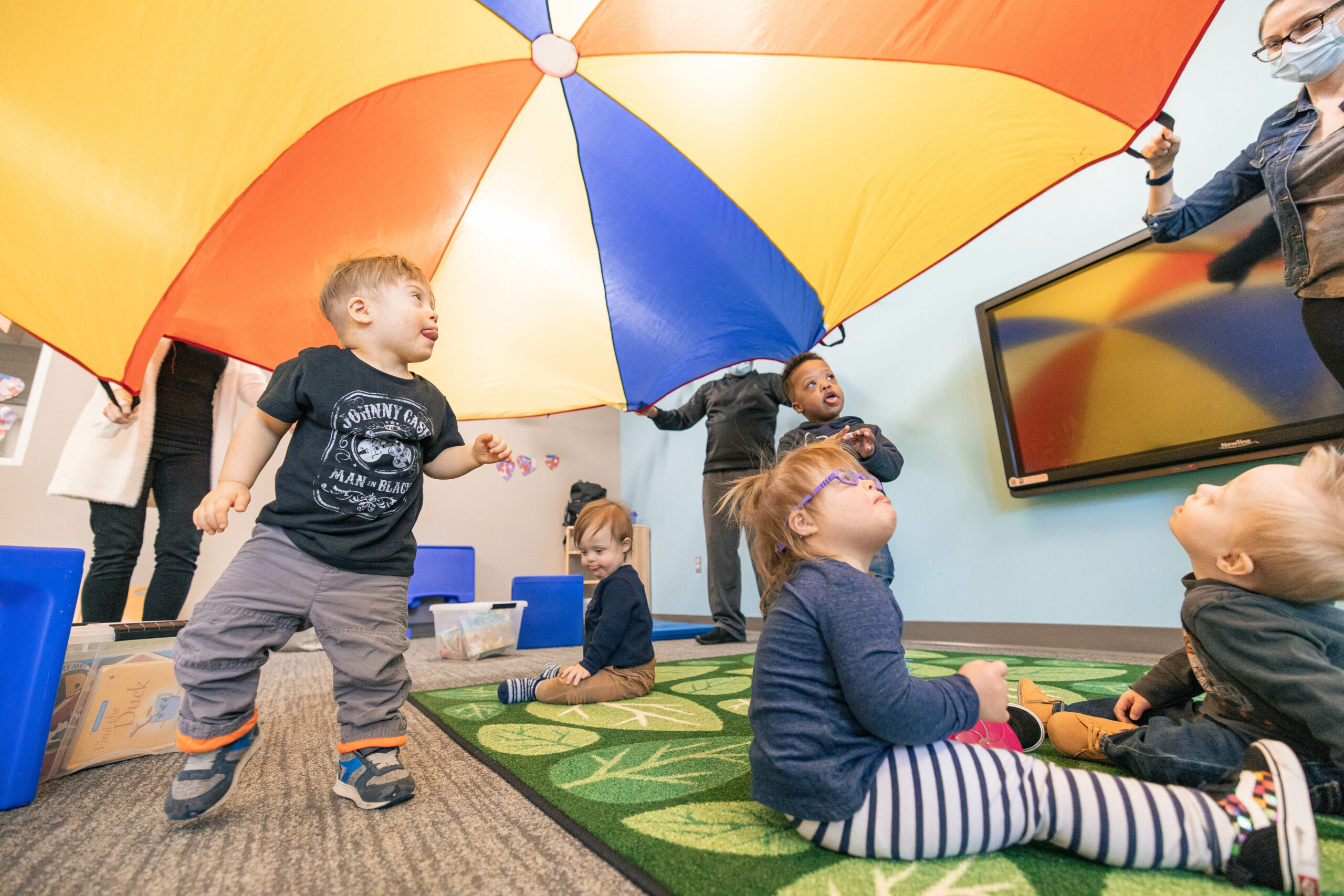 Group of toddlers in an early intervention class watching a play parachute go up and down
