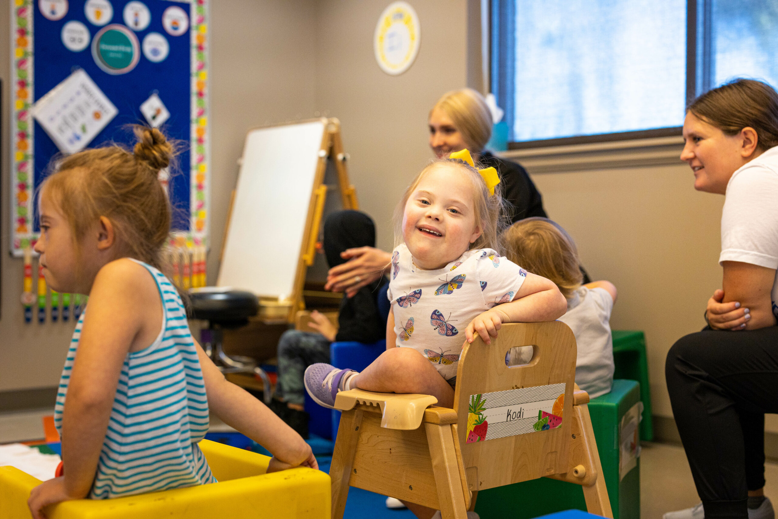 Little girl with Down Syndrome smiling in her seat during circle time in an early intervention classroom