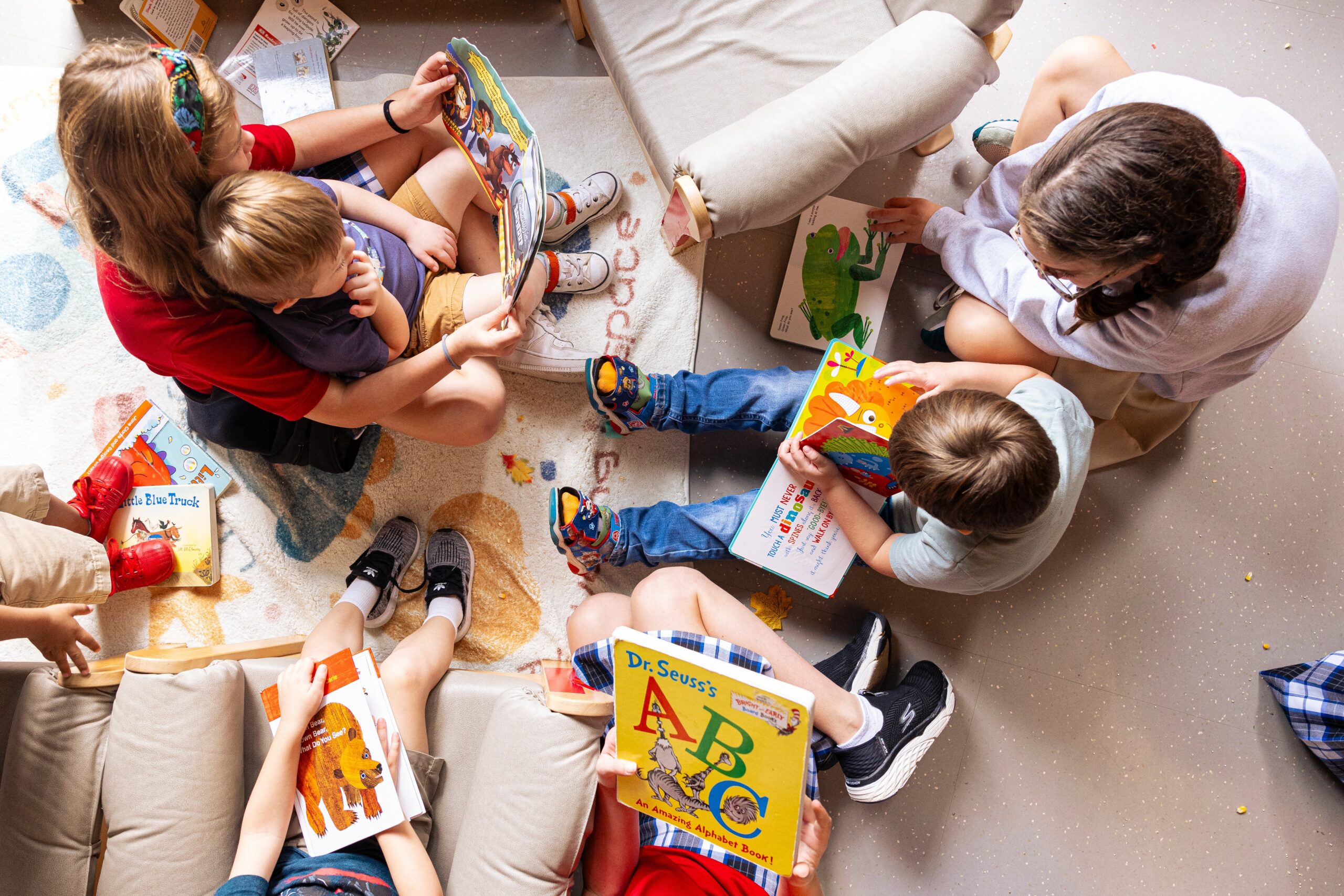 group of children sitting in the floor together looking at colorful children’s books